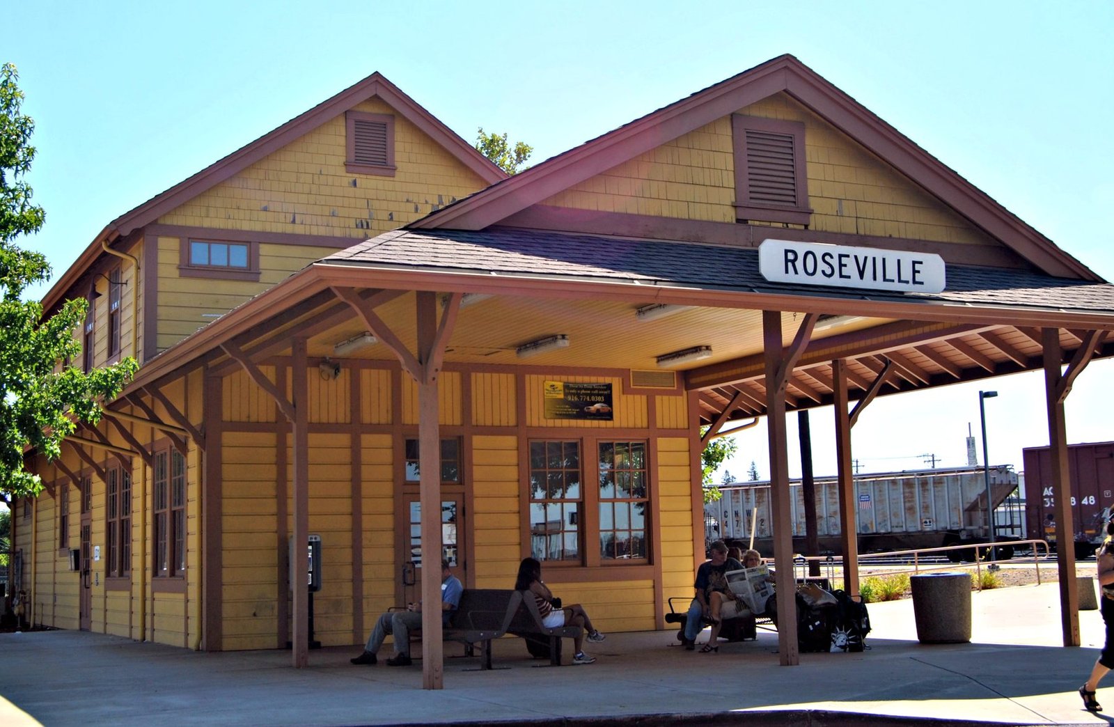 Travelers waiting on the platform of a historic community rail depot